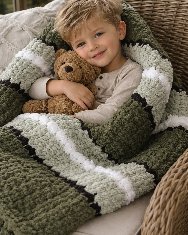Child holding a teddy bear wrapped in a green and white striped blanket on a wicker chair.