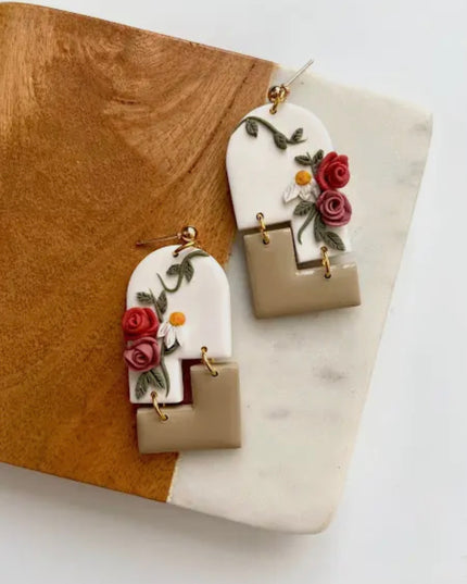 Floral-themed earrings on a marble and wood surface